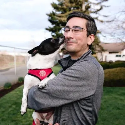 A team member hugging a black and white terrier
